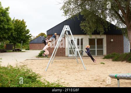 Four kids swinging on the playground on a sunny day Stock Photo