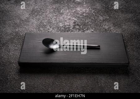 a black table little tea Spoon on a wooden podium. stylish minimalistic still life. Stock Photo