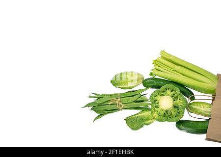 Green colored vegetables flying from the kraft paper bag isolated on white Stock Photo