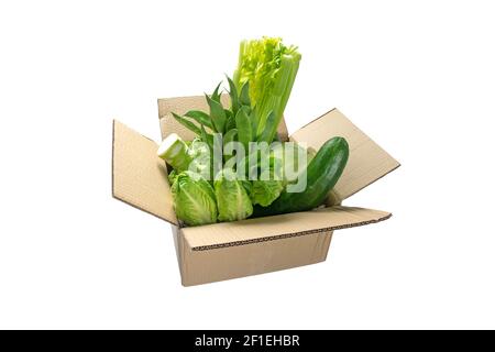 Green colored vegetables in the cardboard box isolated on white. Food purchase and delivery. Stock Photo