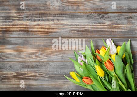 Tulip flowers on a wooden background. Spring flowers composition. Background with copy space. View from above. Stock Photo