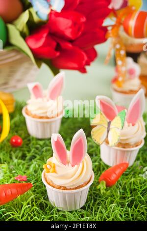 Easter funny bunny cupcakes. Easter celebration festive table. Basket of flowers tulips on the background Stock Photo