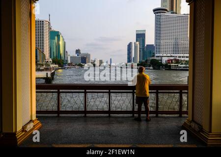 An elderly man looks out at the Chao Phraya river in Bangkok, Thailand Stock Photo