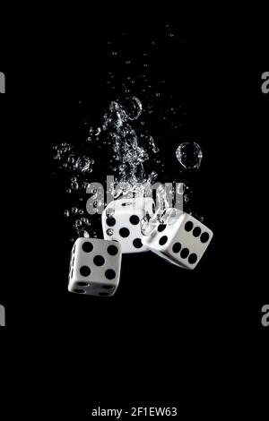 Dices thrown in water with air bubbles on black background Stock Photo