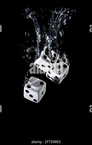Dices sinking in water with bubbles on black background Stock Photo