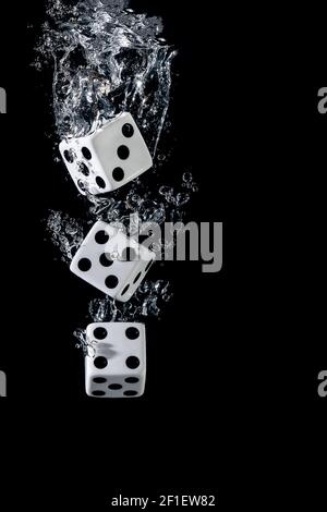 Dices sinking in water with bubbles on black background Stock Photo