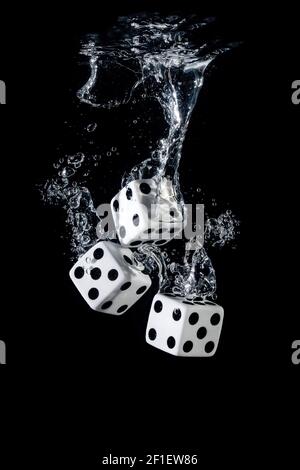 Dices sinking in water with bubbles on black background Stock Photo
