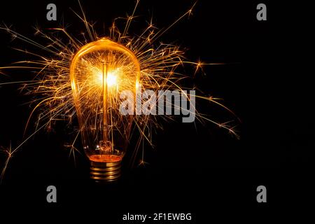 Incandescent light bulb with emitting sparks on black background Stock Photo