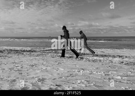 Two people ski on the beach after heavy snowfall in the country. Stock Photo