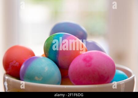 Close up bowl of brightly colored Easter eggs on diplay Stock Photo