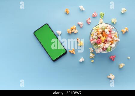 top view of smart phone and popcorn on blue background  Stock Photo
