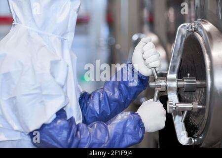 Cropped side view portrait of male worker wearing protective suit while operating equipment at chemical plant, copy space Stock Photo