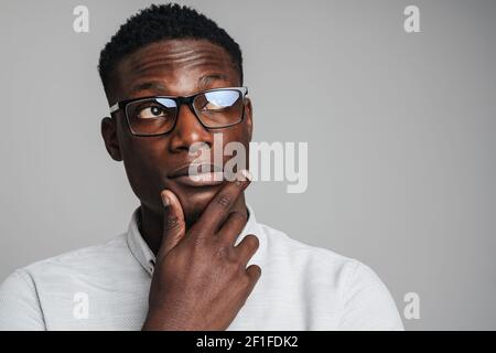 Closeup portrait of young african man thinking deeply about something isolated on gray background Stock Photo