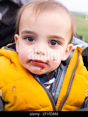 Young toddler of 17 months of age with chocolate on his face after eating a cake treat Stock Photo