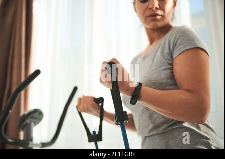 Close-up woman exercising with a harness for fitness, doing exercises on the muscles of the arms Stock Photo