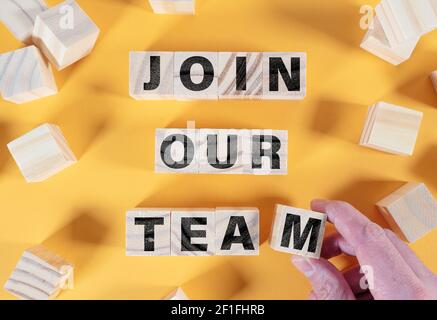 directly above view of text JOIN OUR TEAM on wooden blocks against orange background Stock Photo