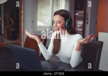 Happy young woman with headset explain problem in home office, online communication Stock Photo