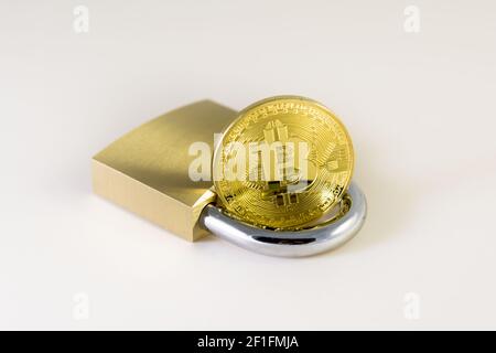 Bitcoin over a padlock isolated on white Stock Photo