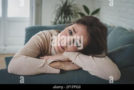 Depressed sad attractive woman crying on sofa couch at home feeling lonely tired and worried suffering depression in mental health, loneliness and iso Stock Photo