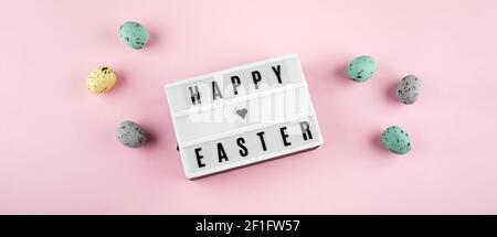 Easter spring holiday greeting card. Lightbox with text Happy Easter. colorful easter eggs, rabbits. Flat lay, top view. Banner Stock Photo