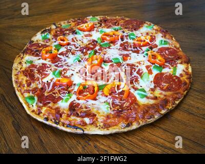 Whole homemade pepperoni and cheese pizza with peppers. Stock Photo