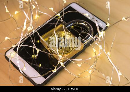 Bitcoin and padlock over a screen with a web of connected dot lights on the foreground Stock Photo
