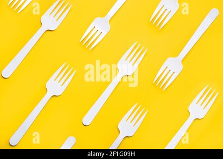 Geometric pattern made with white plastic forks on yellow background Stock Photo