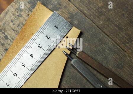 Set of leather 1-hole punchers on piece of leather and liner. Instruments of leather master working process. Stock Photo