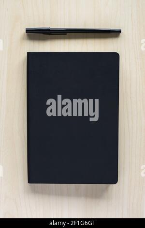 Black notebook and pen on wooden table. Stock Photo