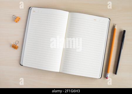 Open notebook on wooden table with stationery. Stock Photo