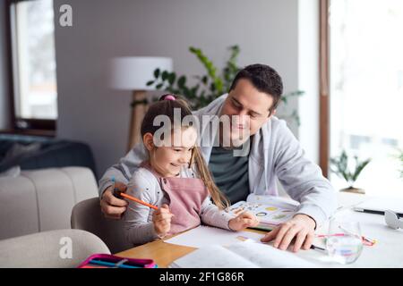 Father helping daugther with homework indoors at home, distance learning. Stock Photo
