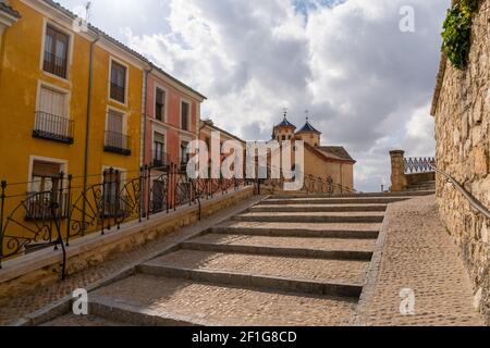 Old cobblestone stairs leading into the heart of the old city center of Cuenca witl El Salvador church in the background Stock Photo