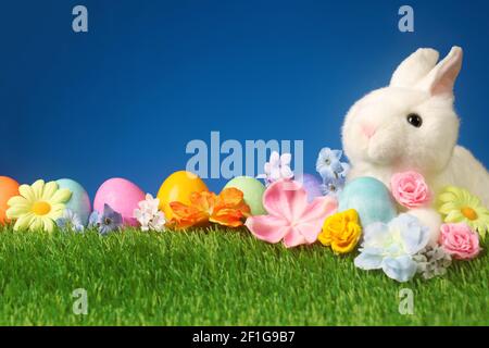 Festive Easter background with rabbit, flowers, and colorful eggs Stock Photo
