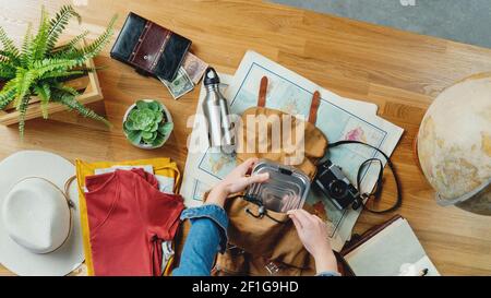 Top view of young woman packing for vacation trip holiday, desktop travel concept. Stock Photo