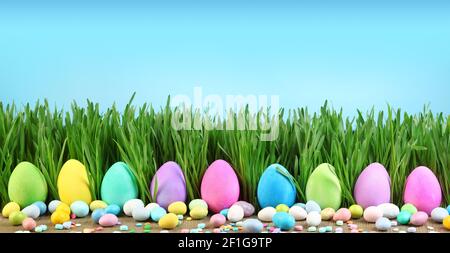 Painted Easter eggs in grass and colorful Easter candy. Stock Photo