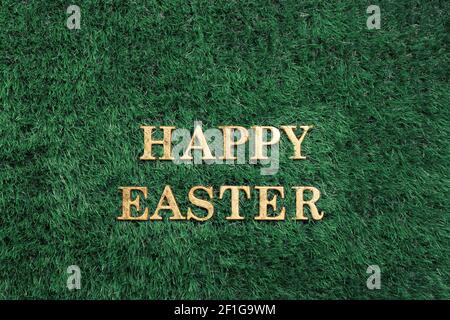 Happy Easter gold text laying in green grass Stock Photo