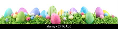Painted Easter eggs and decorations on arranged on Easter grass. Horizontal banner isolated on white. Stock Photo