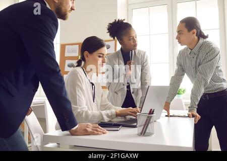 Young colleagues discussing a startup idea or a new business project by writing data to a laptop. Stock Photo