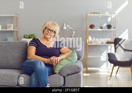 Smiling mature woman or grandmother sitting on sofa at home Stock Photo