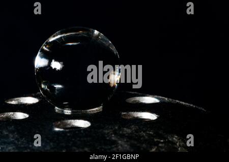 Glass sphere in equilibrium on metal support in the black background Stock Photo
