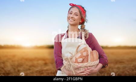 Female farmer standing wheat agricultural field Woman baker holding wicker basket bread eco product Baking small business Caucasian person dressed red Stock Photo