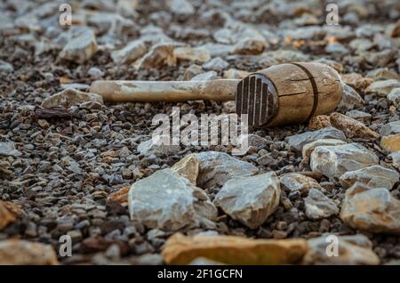 A used meat tenderizer in the stones on the ground Stock Photo
