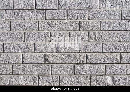 Beautiful grey stone wall background texture with different shapes, illuminated by the sun Stock Photo