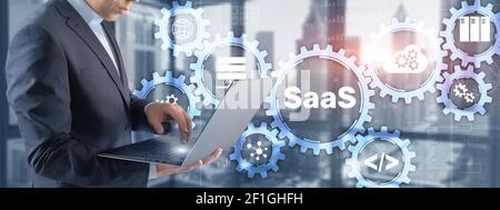 SaaS Software as a Service concept with hand pressing text. Stock Photo