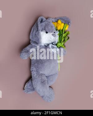 hare with flowers on a pink background tulip toy spring rabbit hare, greeting card white space, birthday Dyed text hunt, pastel paint Stock Photo