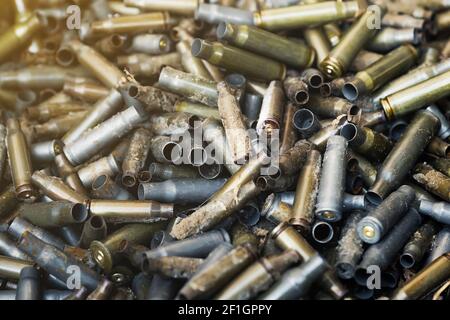 Empty carbine or rifle cartridges. A large number of cases. Background of brass ammunition cartridges to illustrate armed conflict, war or shooting. Stock Photo