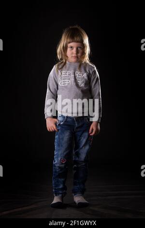 Smiling blonde little girl with pink dress on grey and black and white background photoshoot in studio. Stock Photo