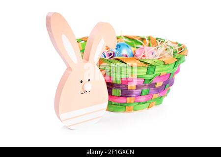 Close up of Easter bunny and a basket filled with colorful Easter eggs with polka dots, isolated on white background. Fun, colorful Easter celebration Stock Photo