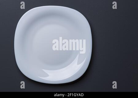 Close up view of white  square shaped plate on black background. Black and white background. Eating concept background. Stock Photo