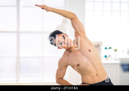 Muscular Asian young man doing  exercises at home Stock Photo